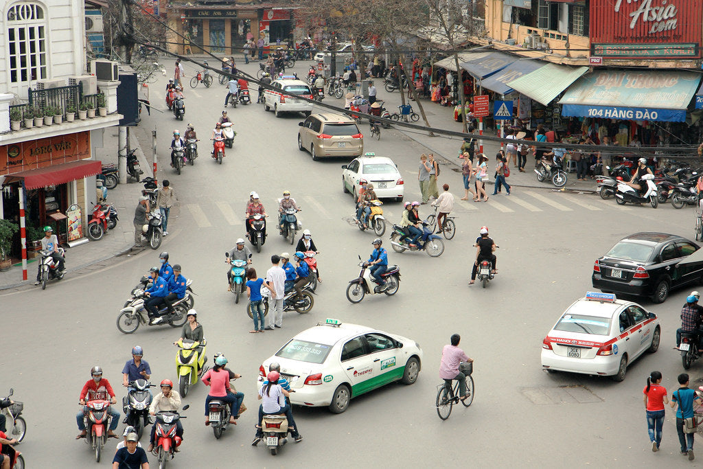 Motorbikes, taxis and pedestrians crossing a busy intersection in Hanoi's Old Quarter, seen from above